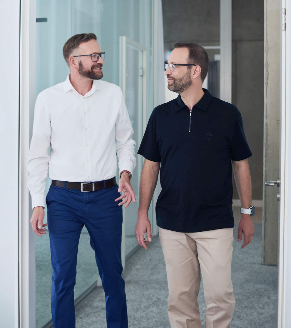 Zwei Mitarbeiter der ear laufen nebeneinander einen Bürogang entlang und unterhalten sich dabei